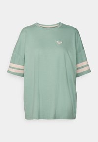 Mátově zelené oversized tričko s kulatým výstřihem, krátkými rukávy a světle růžovými pruhy na rukávech. Na hrudi se nachází malé srdíčkové logo.