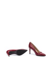 Zapatos de tacón alto de cuero rojo con punta afilada y un acabado suave. Cuentan con una suela de goma negra texturizada para mayor tracción.