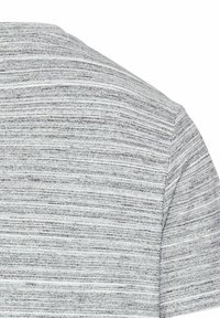 Gråstribet strikket stof, kortærmet design, tekstureret overflade med varierende nuancer af grå og hvid. Ingen bemærkelsesværdigt hardware eller accenter.