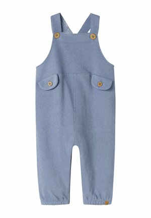 Salopette en tricot bleu avec des bretelles ajustables, deux poches avant avec des rabats arrondis et des accents en bois. Manches élastiquées aux chevilles.