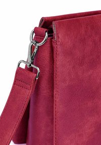 Red faux leather handbag with a smooth texture, silver hardware, and an adjustable strap. Features a zip closure at the top.
