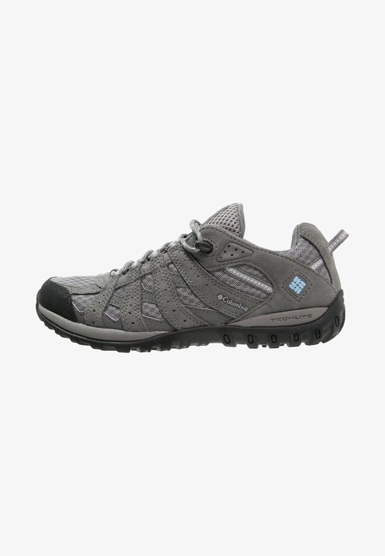 Chaussure de randonnée Columbia grise avec tige en mesh et suède, fermeture à lacets, semelle noire et logo bleu sur le côté, conçue pour les activités de plein air.