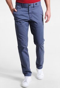 Námořnické modré bavlněné chinos s hladkou texturou, vybavené zipem, předními kapsami a bílými teniskami. Klasický střih s minimálními detaily.