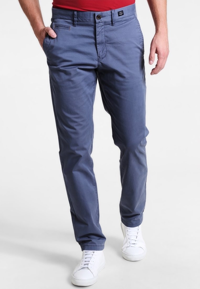 Námořnické modré bavlněné chinos s hladkou texturou, vybavené zipem, předními kapsami a bílými teniskami. Klasický střih s minimálními detaily.
