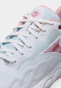 Λευκό αθλητικό παπούτσι με μπλε δίχτυ, ροζ λεπτομέρειες, κόκκινα λογότυπα και λευκά κορδόνια δεμένα από πάνω.