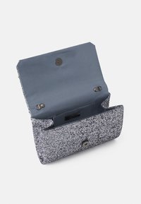 Petit sac pochette pailleté argent avec doublure intérieure gris foncé, fermeture magnétique et crochets métalliques pour une bandoulière.