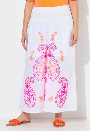 Hvide bukser med vide ben med orange og pink paisley-broderi, båret med orange sandaler og orange top.