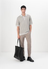 Grå kortermet polo-skjorte med kontrastkrage, beige bukser og en svart lær totebag med glatt tekstur og strukturert design.