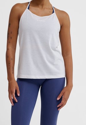 White athletic tank top with a mesh texture, featuring a Halter neck design, and a small logo. Paired with navy blue leggings with vertical lines.