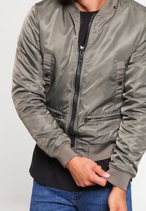 Graue Bomberjacke mit glänzender Oberfläche, Reißverschluss, seitlichen Taschen, gerippten Ärmeln und Saum; verfügt über kontrastierende Einsätze auf der Vorderseite.