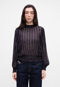 Blusa navy con righe verticali in oro e bronzo. Presenta un collo alto, polsini arricciati e orlo arricciato. Maniche lunghe a palloncino.