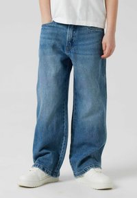 Wijdvallende blauwe jeans van denim met een vervaagde afwerking. Beschikt over een traditionele vijf-pocket ontwerp en zit op de taille.