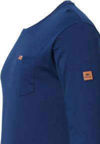 Marineblaues Langarmhemd aus weichem Stoff mit einer Brusttasche und einem braunen Lederetikett am Ärmel. Flachnahtdesign.