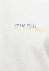 Λευκό ύφασμα με το κείμενο «Oyster Party» σε μπλε και «Marc O'Polo Denim» σε κίτρινο μεταξοτυπωμένο.