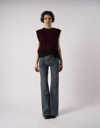 Πλεκτό γιλέκο σε σκούρο κόκκινο και μαύρο με υφασματική υφή, συνδυασμένο με τζιν σε ίσια γραμμή σε μπλε απόχρωση και μεταλλικό κούμπωμα.