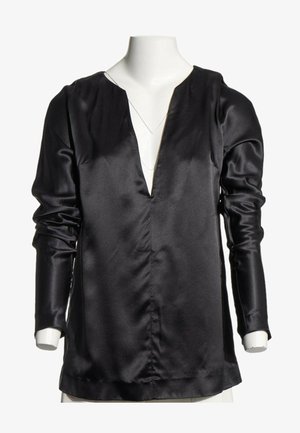 Blouse noire en satin à manches longues avec un col en V profond, exposée sur un mannequin torse blanc.