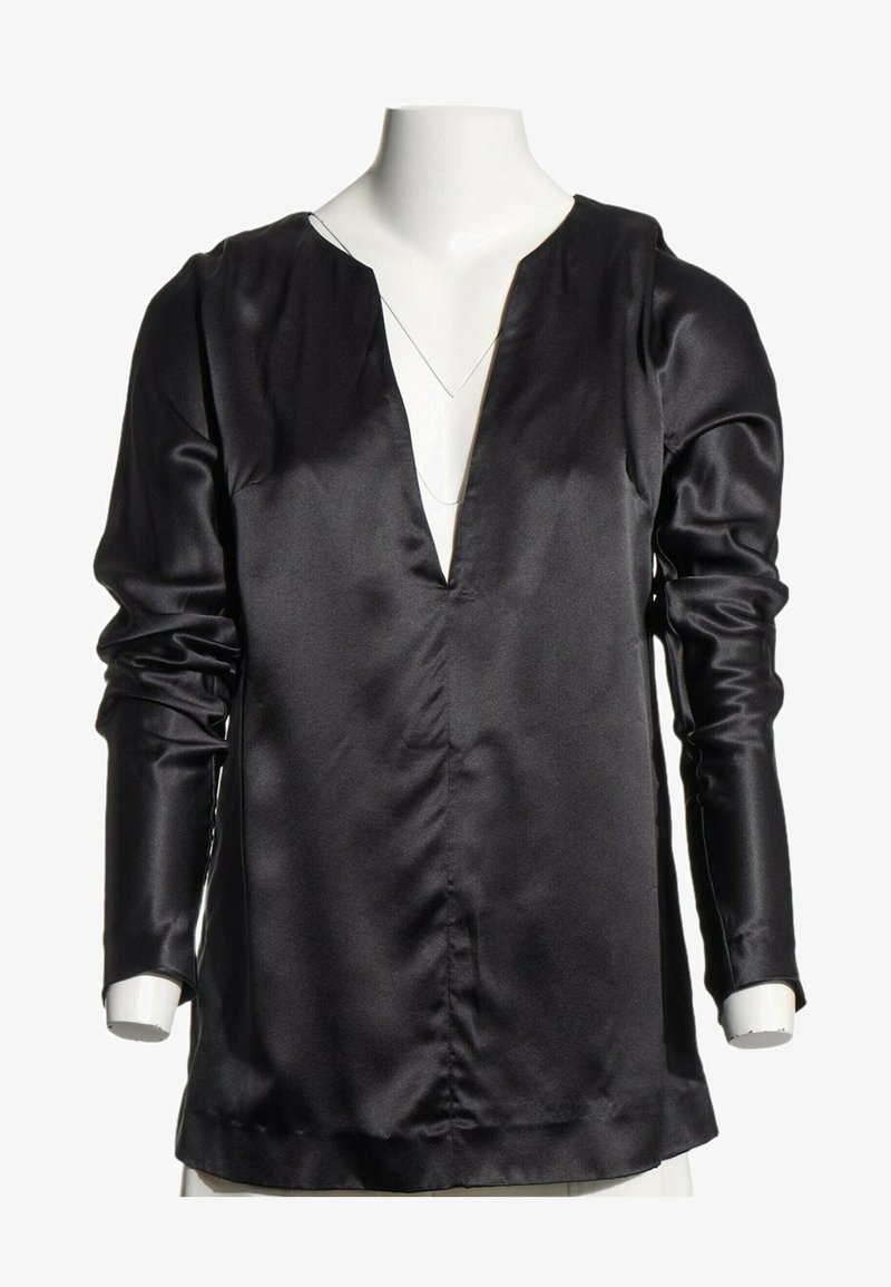 Blouse noire en satin à manches longues avec un col en V profond, exposée sur un mannequin torse blanc.