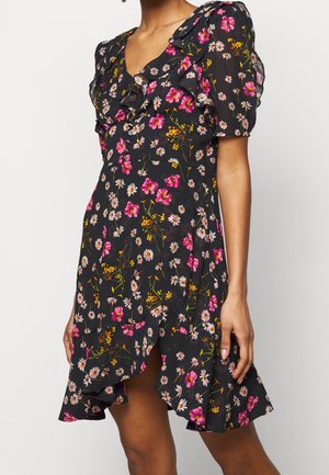 Robe noire à motifs floraux roses et blancs, à encolure et manches volantées, avec un ourlet évasé présentant une fente latérale.