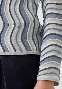 Gestrickter Pullover mit Wellenmustern in Hellgrau, Blau- und Marineblau-Tönen. Verfügt über strukturierte Streifen und einen gerippten Saum. Lange Ärmel mit umgeschlagenen Bündchen.