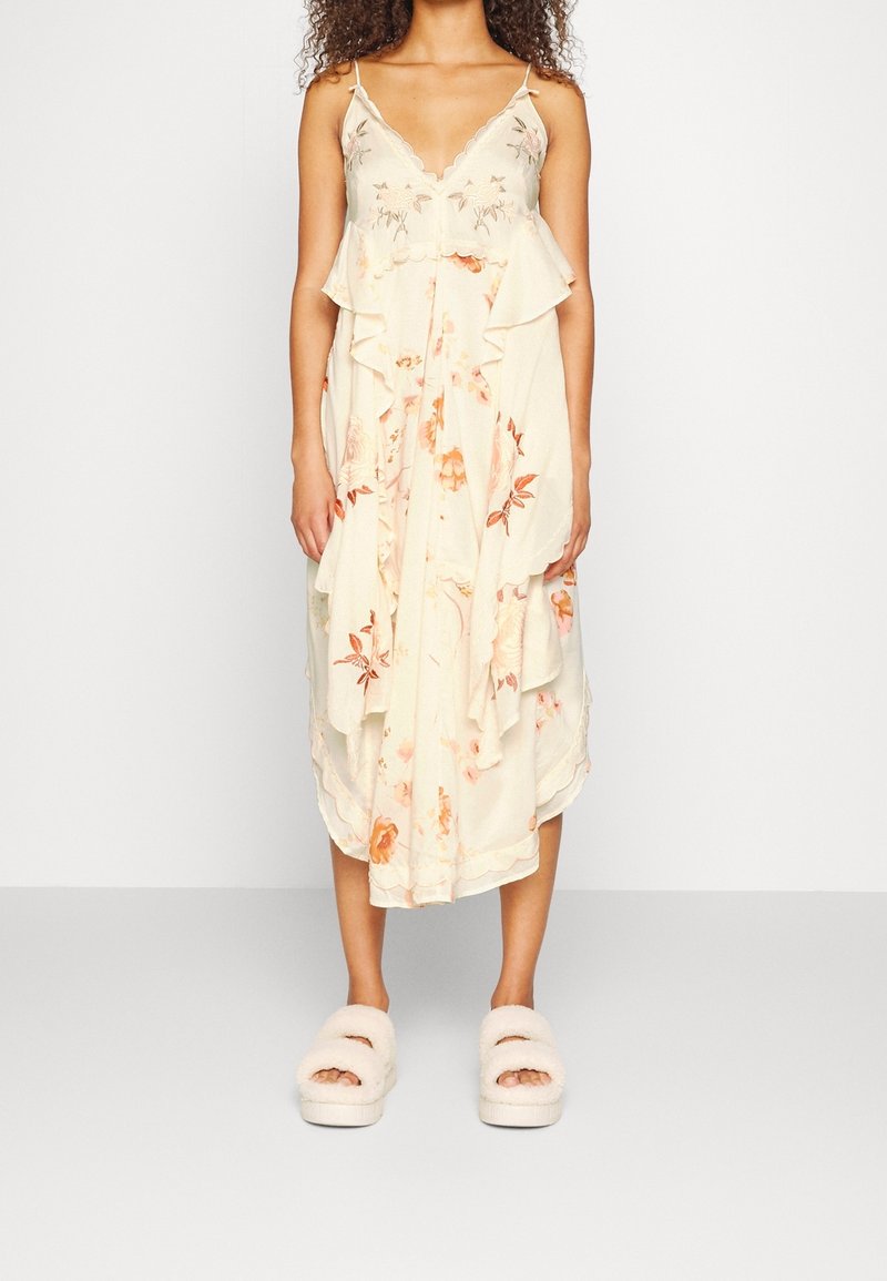 Blommig maxiklänning i mjukt, lätt tyg med v-ringning, volanglager och orange blommönster. Matchas med fluffiga vita slidesandaler.