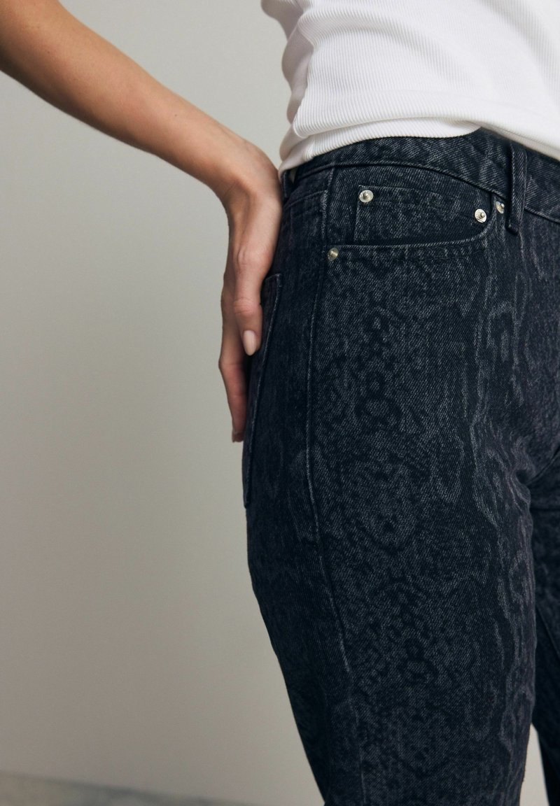 Jeans negre cu imprimeu de șarpe, confecționați din denim, având talie medie, design cu cinci buzunare și detalii din metal argintiu.
