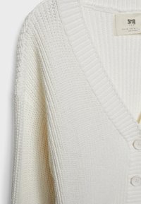 White knitted cardigan with a V-neck, ribbed collar, and five button closure. Features textured fabric and a relaxed fit.