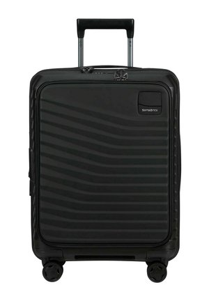 Valise rigide noire avec poche zippée à l'avant, poignée télescopique, quatre roues et logo Samsonite dans le coin supérieur droit.