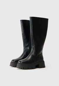 Cizme din piele neagră, până la genunchi, cu un finisaj neted, talpă din cauciuc robustă și fermoar lateral pentru o îmbrăcare ușoară. Prezintă un design vertical elegant.