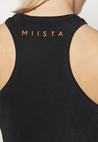 Czarny bezrękawnik o okrągłym dekolcie, z napisem "MIISTA" pomarańczowymi literami na plecach. Miękki, elastyczny materiał.
