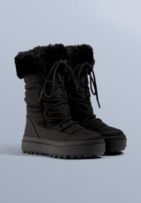 Schwarze, gepolsterte Winterstiefel mit Kunstpelzbesatz, ausgestattet mit einer dicken Sohle und einem Schnürdesign für sicheren Halt. Glatte Textur mit strukturierter Sohle.