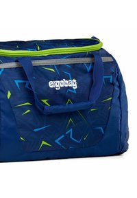 Blaue Duffel-Tasche mit grünen Akzenten, geometrischen Mustern, grauem Reißverschluss und zwei Griffen. Mit "ergobag"-Logo in weißem Stick.