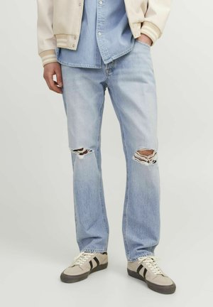Light blue distressed jeans with frayed knee rips, paired with a denim shirt and cream bomber jacket, featuring striped cuffs and snap buttons.