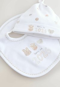 White cotton baby bib and hat set, featuring pastel-colored embroidered designs of animals and "born in 2026" text. Soft texture.