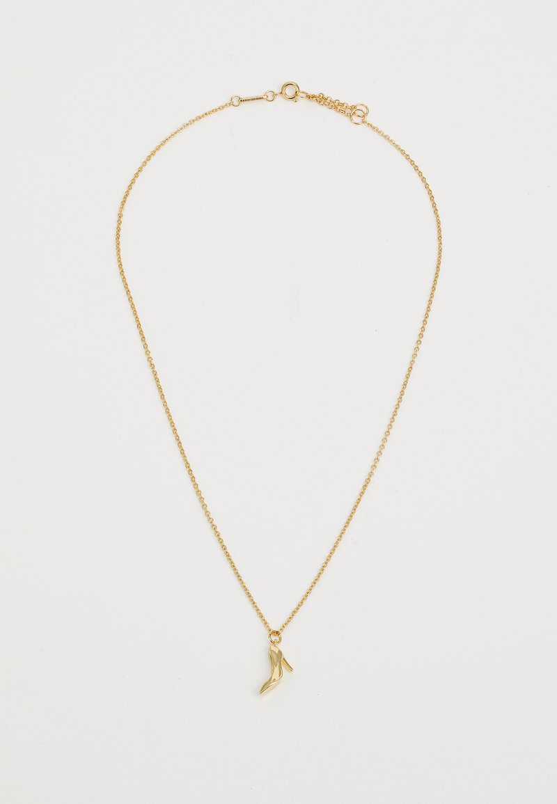 Collar de cadena de oro con un pequeño charm de tacón alto, que presenta una superficie suave, acabado brillante y delicados eslabones en un diseño estándar.