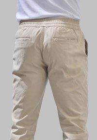 Lichtbeige broeken van een zachte katoenmix, met een elastische tailleband, twee achterzakken en een gladde, licht kreukvrije textuur.