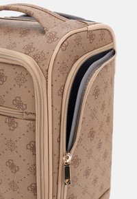 Borsa da viaggio in tessuto marrone con un motivo testurizzato, dotata di una cerniera dorata con un tirazip nero e accenti beige. Forma rettangolare compatta.