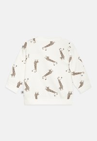 Felpa bianca con una stampa di giraffa marrone ripetuta. Maniche lunghe con polsini a costina e scollatura rotonda. Materiale in morbido cotone.