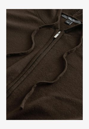 Ruskea vetoketjuhuppari, joka on valmistettu pehmeästä kankaasta. Sisältää ribbitekstuurin kauluksessa ja sileän vartalossa, sekä metallivetoketjun.