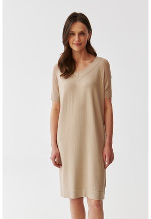 Beiges knie-langes Kleid aus weichem Strickmaterial, mit V-Ausschnitt und kurzen Ärmeln, in lockerer Passform und mit subtiler Textur.