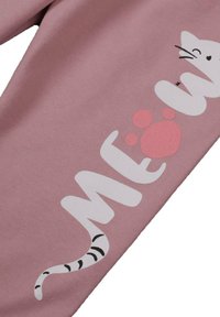 Różowe legginsy bawełniane z białym napisem "MEOW" oraz wzorem w postaci kociego ogona, a także akcentem w postaci różowego odcisku łapy. Miękka, gładka tekstura.