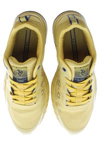 Żółte buty sportowe z teksturowaną cholewką, zaokrąglonym nosem i wzmocnionym piętą. Zawierają sznurowanie i akcenty z logo na języku.