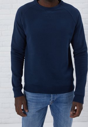 Sudadera de cuello redondo en azul marino con mangas raglán y puños y dobladillo acanalados. Material suave, diseño minimalista sin logotipos visibles.