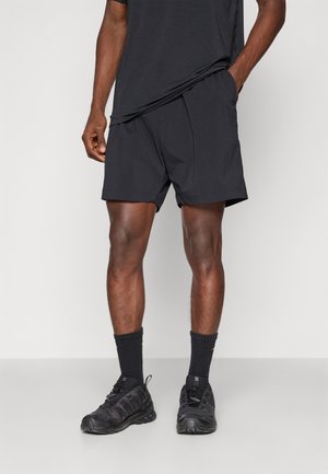 Shorts de sport noirs avec une taille élastique, associés à des chaussettes texturées noires et des chaussures. Le haut est un t-shirt noir à manches courtes assorti.
