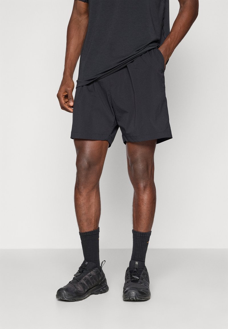 Black athletic shorts with an elastic waistband, paired with black textured socks and shoes. The top is a matching black short-sleeve shirt.