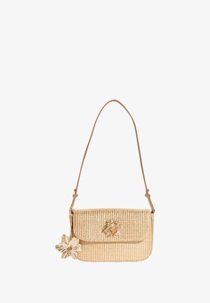 Proplétaná béžová kabelka s dlouhým popruhem, zdobená zlatým květinovým přívěskem a dekorativním zlatým květinovým zdobením na klopě.