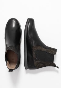 Botas de cuero negras hasta el tobillo con paneles laterales texturizados en negro, gomas elásticas y una suela de goma de perfil bajo. Presenta un acabado suave.