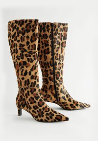 Bottes montantes en imprimé léopard en matériau doux, dotées d'un bout pointu, d'un talon carré et d'une fermeture éclair à l'arrière.
