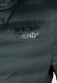 Giacca imbottita nera con tessuto lucido e la scritta nera "WRONG FRIENDS" stampata sul retro.