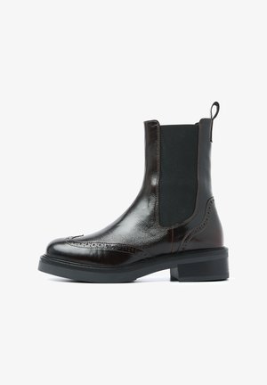Bruine leren Chelsea-boot met elastische zijpanelen, decoratieve brogue-details en een stevige zwarte rubberen zool. Gladde afwerking en robuust ontwerp.