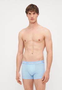 Boxeri de culoare albastru deschis, confecționați dintr-un material moale, având o potrivire strânsă și un elastic în talie cu logo-ul "HOLLISTER" în alb.